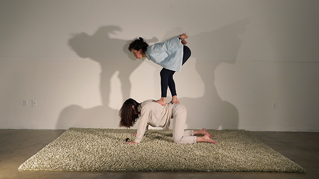 A woman down on knees and elbows and another woman on top of her