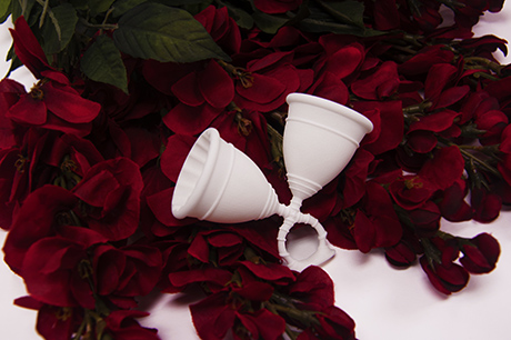ring made of two diva cup-like shapes against red flowers