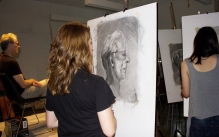 Student working on a charcoal portrait of a professional model