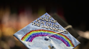 Mortar board with a gem rainbow and lettering that reads "It's kind of fun to do the impossible"