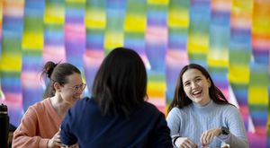 Three students sitting in the Tyler Cafe laughing with each other