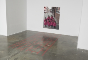 Red tape in Chinatown sidewalk pattern on the floor with a large digital photo print of a little Chinese girl repeated.