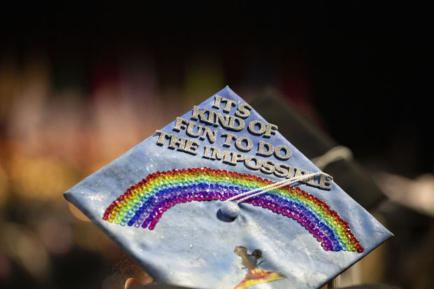 A mortar board with a rainbow made of gems and lettering that reads "It's kind of fun to do the impossible"