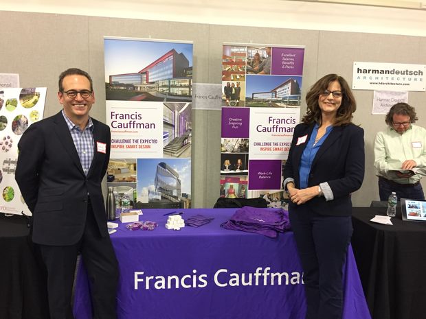 Two representatives from FCA Architects stand in front of their Career Fair booth.
