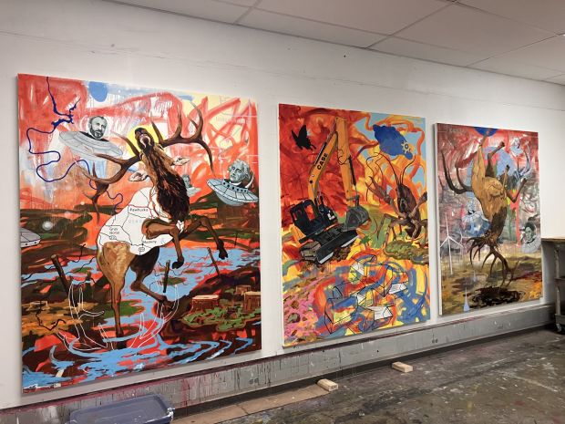 Three large-scale paintings by Norman Akers lean against a studio wall