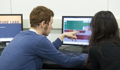students discussing designs on computer