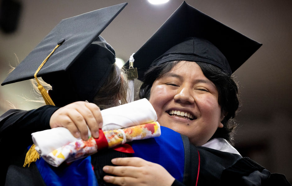 A graduate hugging a faculty member after receiving their diploma