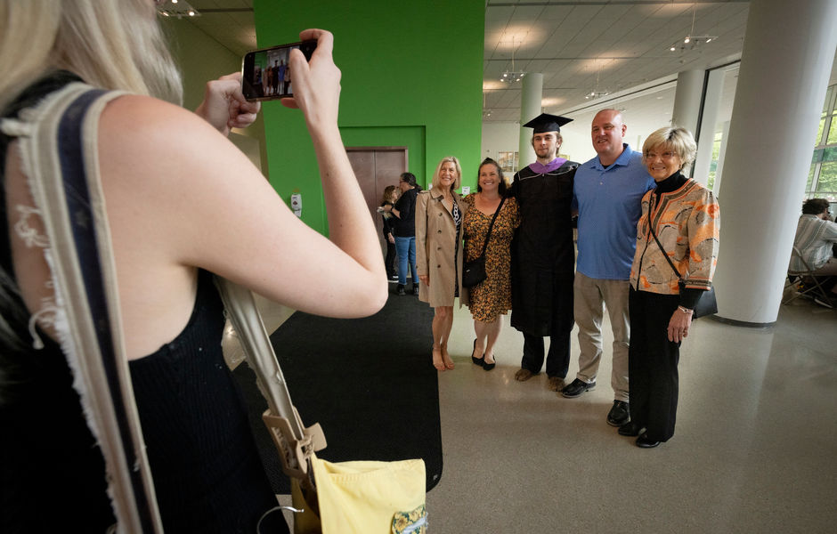 A graduate poses for a photo with family members at the pre-graduation reception