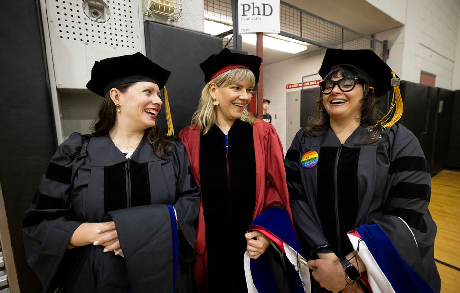 Three PhD graduates standing together talking and smiling 