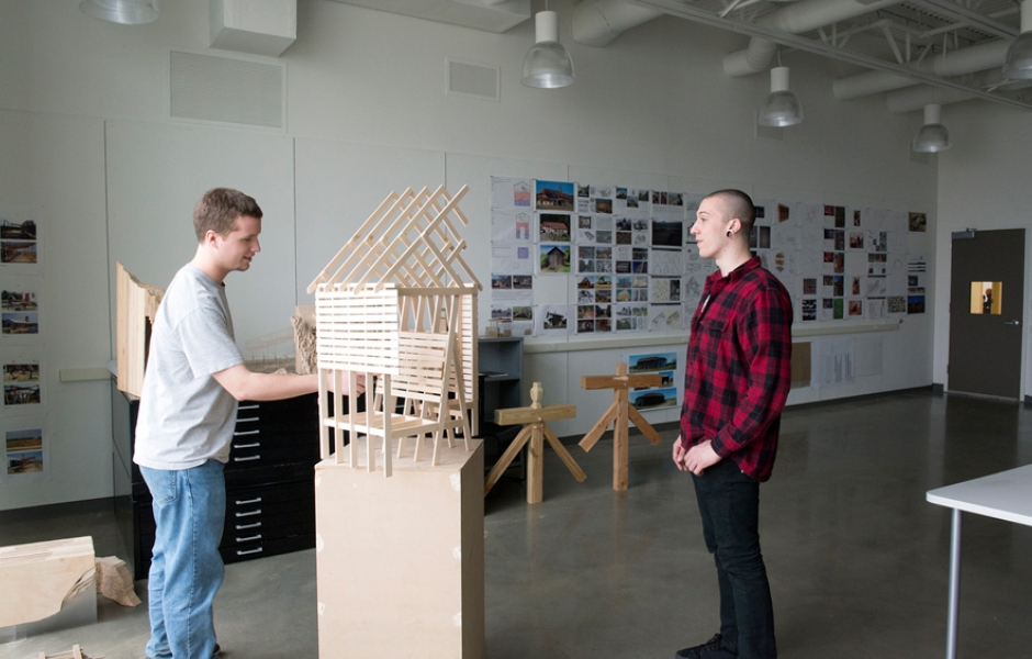 two male students discussing wooden model