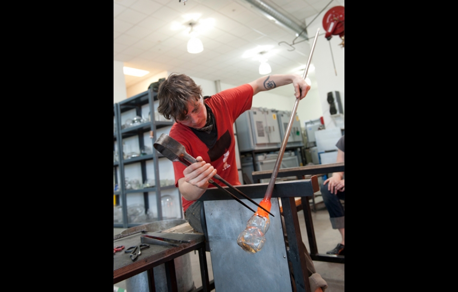 student shaping blown glass