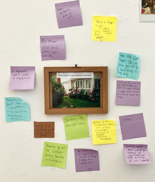 Framed photo of a building with text that reads "What is one of your earliest memories?" surrounded by sticky notes with handwritten answers on them