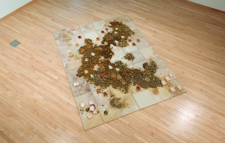 Board of clay tiles on the floor, with loose mineral pigments and ceramic pieces spread over the top