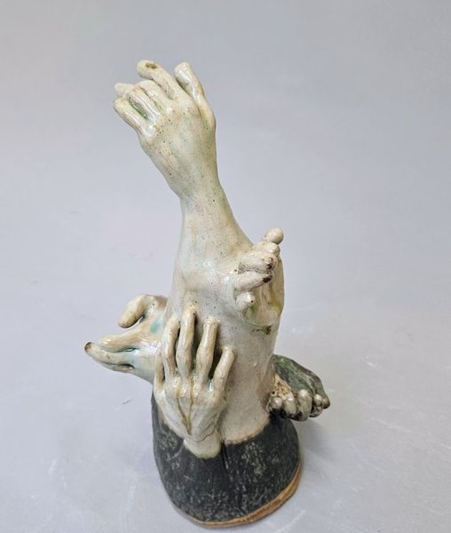 Sculpture of multiple hands morphed together and emerging