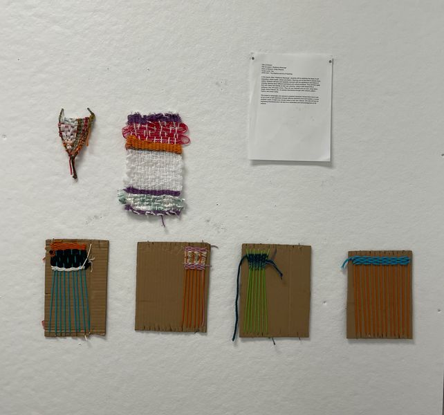 Multiple small in-progress weaving projects hanging on a wall