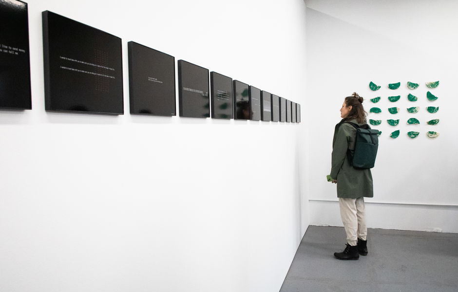 A person stands in front of a wall with a series of photographs on it