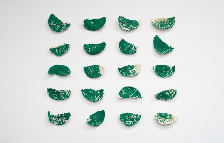 A grid of pitas pinned to the wall with green ink screenprinted onto them