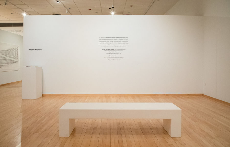 An empty exhibition space with a passage of text printed on a wall