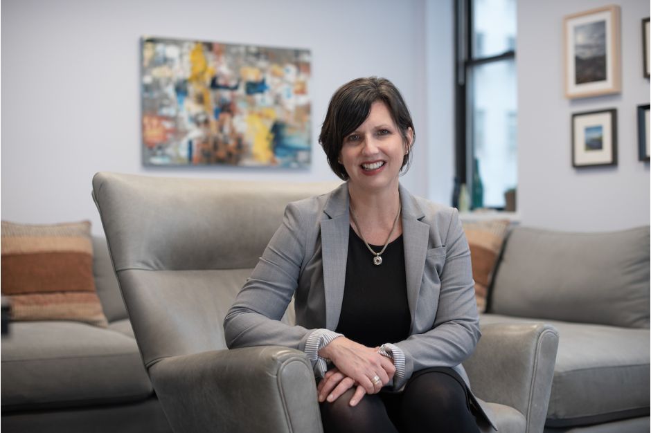 Kathryn Snyder seated on a sofa smiling at the camera