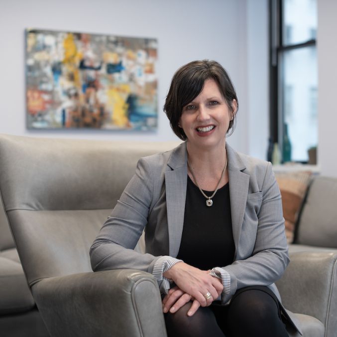 Kathryn Snyder seated on a sofa smiling at the camera