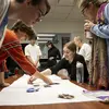 Metals students looking and pointing at objects on a table