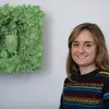 Amber Cowan smiling at the camera in front of artwork