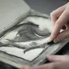 closeup of a student's hands drawing with charcoal in a sketchboo
