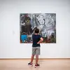 Young person standing in front of a painting in a gallery