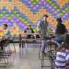 People sitting at tables in a cafe with a colorful patterned wall in the background