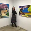 Portrait of Julia Clift standing in a gallery with two paintings