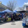 A street with spaces under blue tents covering their outdoor market stalls