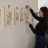 Printmaking graduate student hanging up prints on a wall in their studio