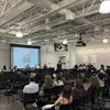 Panel discussion in front of a large group, with a projection on the screen in the background