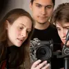 Three students looking through a camera set up on a tripod