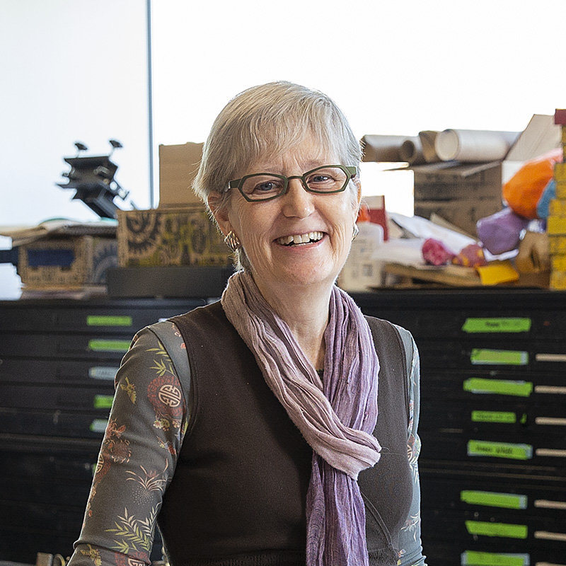 Hester standing in her printmaking studio smiling at the camera.