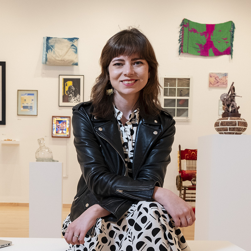 Faith Kellermeyer sitting in a Tyler art gallery, smiling at the camera