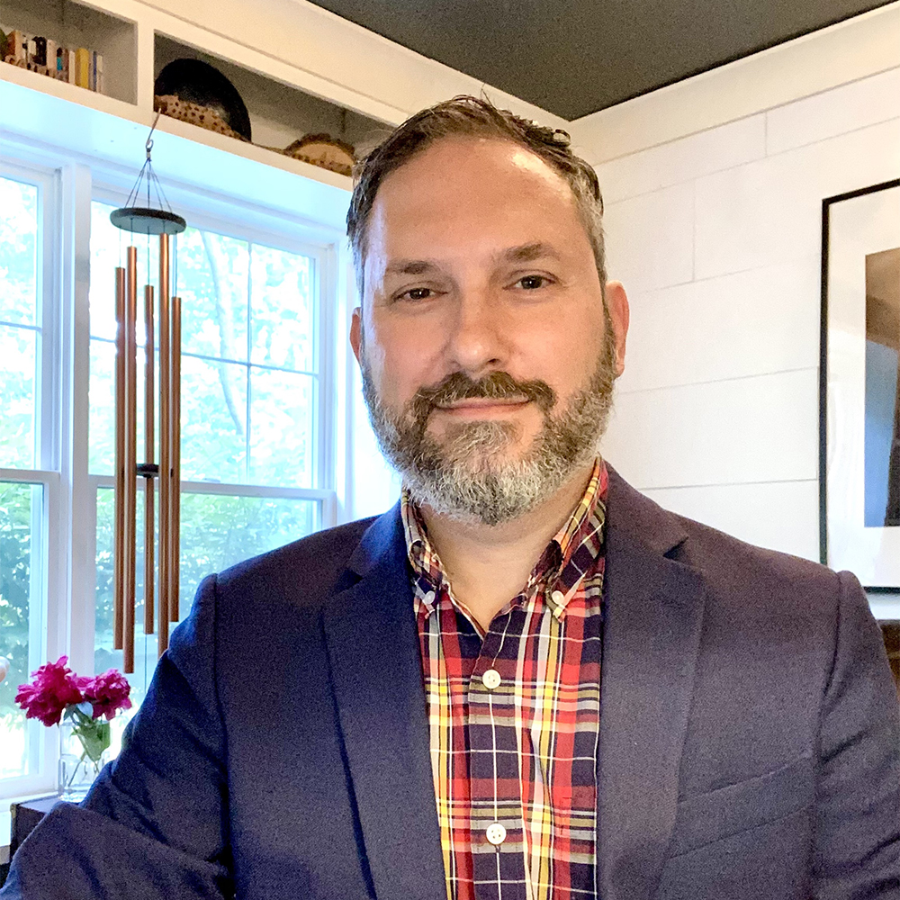 Portrait of Matthew Palczynski wearing a blazer and a plaid shirt